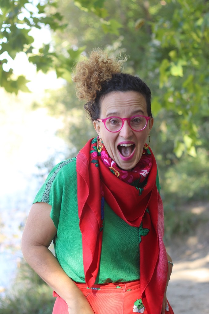 Caroline Robineau, lunettes roses et foulard rouge, en train de s’exclamer