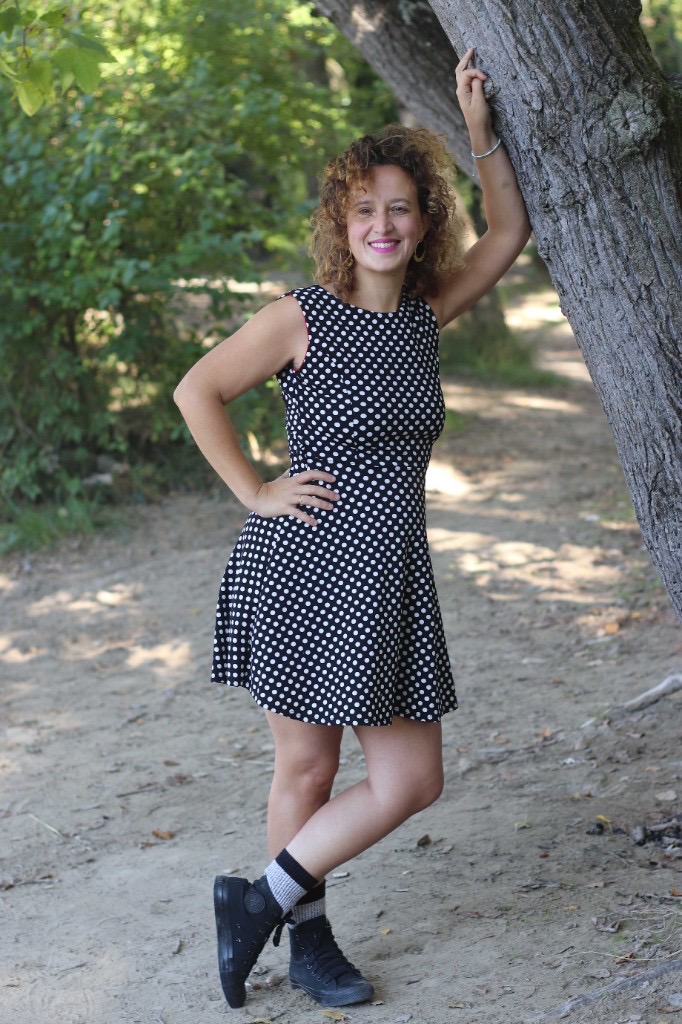 Caroline Robineau en robe à pois, appuyée à un arbre